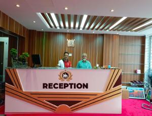 two men standing behind a reception desk at Hotel In Need - Near to the US France Italy Saudi Embassy and Airport in Dhaka