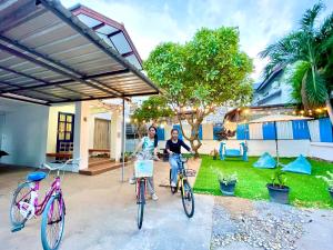 dos mujeres sentadas en sus bicicletas delante de una casa en Heartbeat Crypto Jomtien 05, en Jomtien Beach