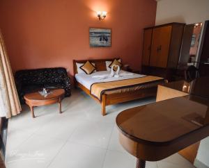a bedroom with a bed and a couch and a table at Renzo's Inn in Calangute
