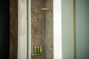 a bathroom with a shower with green bottles on a shelf at EVOLUTION Cascais-Estoril Hotel in Estoril