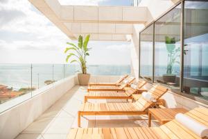 a balcony with wooden chairs and a view of the ocean at EVOLUTION Cascais-Estoril Hotel in Estoril