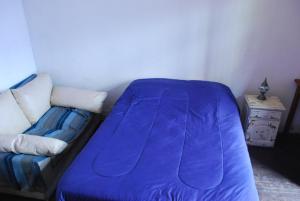 a bed with a blue blanket next to a couch at Lunfardo Boquense in Buenos Aires
