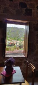 a vase of flowers sitting on a table in front of a window at Oforasteiro in Mucugê