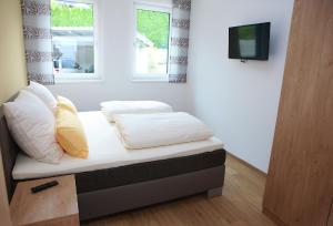 1 cama con sábanas blancas y almohadas en una habitación en Appartements Dullnig, en Flattach