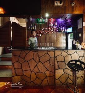 a boy standing behind a counter in a bar at Renzo's Inn in Calangute