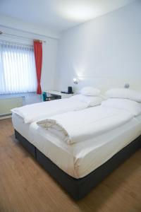 a large white bed in a room with a red curtain at AP Hotel Viernheim Mannheim am Kapellenberg in Viernheim