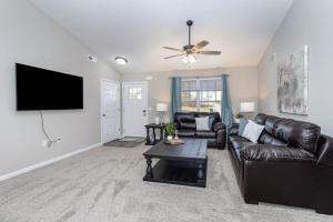 a living room with a leather couch and a flat screen tv at Home among the Nook in Hamilton Ohio in Hamilton