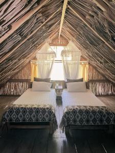 a bedroom with two beds in a thatched room at Reserva Natural El Matuy in Palomino