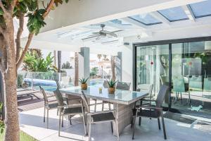 een eetkamer in de openlucht met een glazen tafel en stoelen bij Villa Stefy by Bedzy in Galé