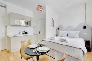 1 dormitorio blanco con 1 cama, mesa y sillas en Résidence des Poissonniers, en París