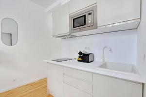 - une cuisine blanche avec évier et four micro-ondes dans l'établissement Résidence des Poissonniers, à Paris