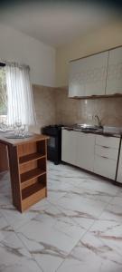 una cucina con armadi bianchi e un tavolo in una stanza di Morada dos eucaliptos a Capão da Canoa
