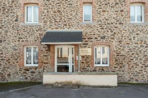 un edificio di mattoni con una porta di fronte di Grain de sable a Saint-Benoît-des-Ondes