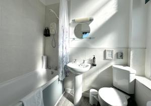 Baño blanco con lavabo y aseo en Station Lounge & Rooms, en Clitheroe