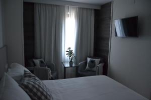 1 dormitorio con 1 cama, 2 sillas y ventana en Hotel Victoria en Puebla de Sanabria