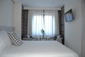 um quarto com uma grande cama branca e uma janela em Hotel Victoria em Puebla de Sanabria