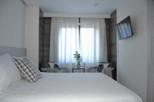 Un dormitorio con una gran cama blanca y una ventana en Hotel Victoria, en Puebla de Sanabria