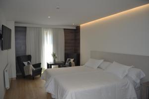 a bedroom with a white bed and two chairs at Hotel Victoria in Puebla de Sanabria