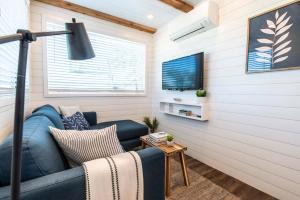 a living room with a blue couch and a tv at The Meadows Shipping Container Home in Bellmead