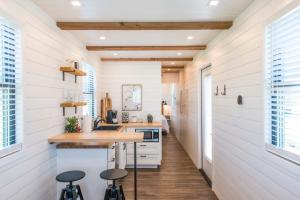 cocina con paredes blancas y suelo de madera en The Meadows Shipping Container Home en Bellmead