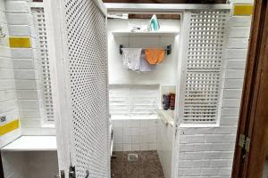 uma pequena casa de banho com um chuveiro com paredes brancas e toalhas brancas em Estilo de vida carioca no Rio de Janeiro