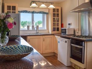 a kitchen with wooden cabinets and a counter top at Cartref Bach in Llanwnen