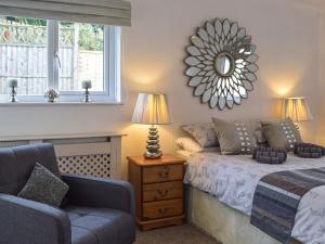1 dormitorio con cama, silla y espejo en Cartref Bach, en Llanwnen