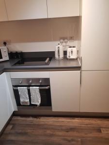 eine Küche mit weißen Schränken und einer Arbeitsplatte in der Unterkunft Stunning 1-Bed Apartment in Brierley Hill in Dudley