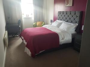 een slaapkamer met een bed met een rode deken en een bureau bij Stunning 1-Bed Apartment in Brierley Hill in Dudley