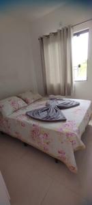 een slaapkamer met een bed met een bloemendeken en een raam bij Morada do bosque in Capão da Canoa