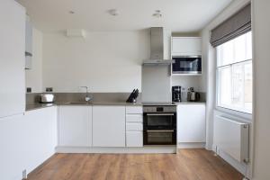 a white kitchen with white cabinets and a window at Sonder Inverness Mews in London