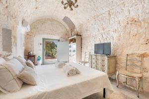 a bedroom with a white bed and a tv at Ca` della Roccia by Perle di Puglia in Ostuni