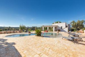 a patio with a pool and chairs and a building at Ca` della Roccia by Perle di Puglia in Ostuni