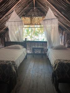 a bedroom with two beds in a straw hut at Reserva Natural El Matuy in Palomino