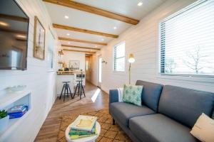 The Pecan Grove Container Home 15 min to Magnolia في Bellmead: غرفة معيشة مع أريكة زرقاء ومطبخ