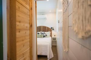 The Pecan Grove Container Home 15 min to Magnolia في Bellmead: غرفة نوم صغيرة بسرير وجدار خشبي