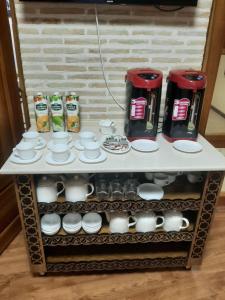 une étagère avec des tasses, des tasses et une cafetière dans l'établissement Old House Hotel, à Boukhara