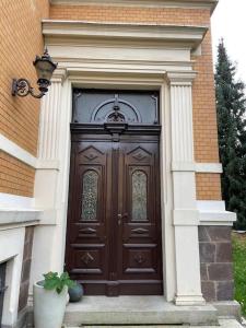 uma grande porta de madeira num edifício com um vaso de plantas em Kleine Wohnung in schöner Villa em Meerane