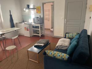 Mas de L'isle في Bédarrides: غرفة معيشة مع أريكة زرقاء ومطبخ