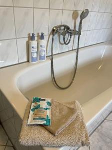 a bath tub with a shower and two bottles of shampoo at Kleine Wohnung in schöner Villa in Meerane
