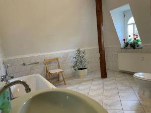 a bathroom with a tub and a toilet and a chair at Kleine Wohnung in schöner Villa in Meerane