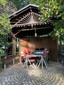 a patio with a table and a grill under a pavilion at Kleine Wohnung in schöner Villa in Meerane