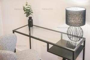 una mesa de cristal con una lámpara y una silla en Riverside Drive Apartment - Grampian Lettings Ltd, en Aberdeen