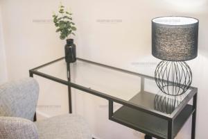 a glass table with a lamp and a chair at Riverside Drive Apartment - Grampian Lettings Ltd in Aberdeen