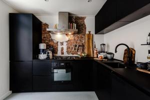 a kitchen with black cabinets and a brick wall at Beach House Alexy Zandvoort in Zandvoort