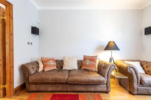 a living room with a brown couch and a lamp at The Artist's House Alma Street in London