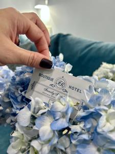 eine Person mit einer Hotelkarte neben blauen Blumen in der Unterkunft Family Residence Boutique Hotel in Lwiw