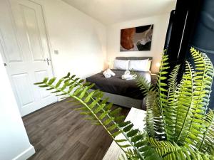 ein Schlafzimmer mit einem Bett und einer grünen Pflanze in der Unterkunft Riverside View by Blue Skies Stays in Middlesbrough