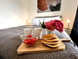 a tray with pancakes and strawberries and flowers on a bed at Riverside View by Blue Skies Stays in Middlesbrough