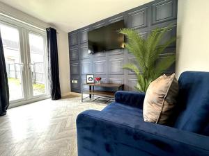 ein Wohnzimmer mit einem blauen Sofa und einem TV in der Unterkunft Riverside View by Blue Skies Stays in Middlesbrough